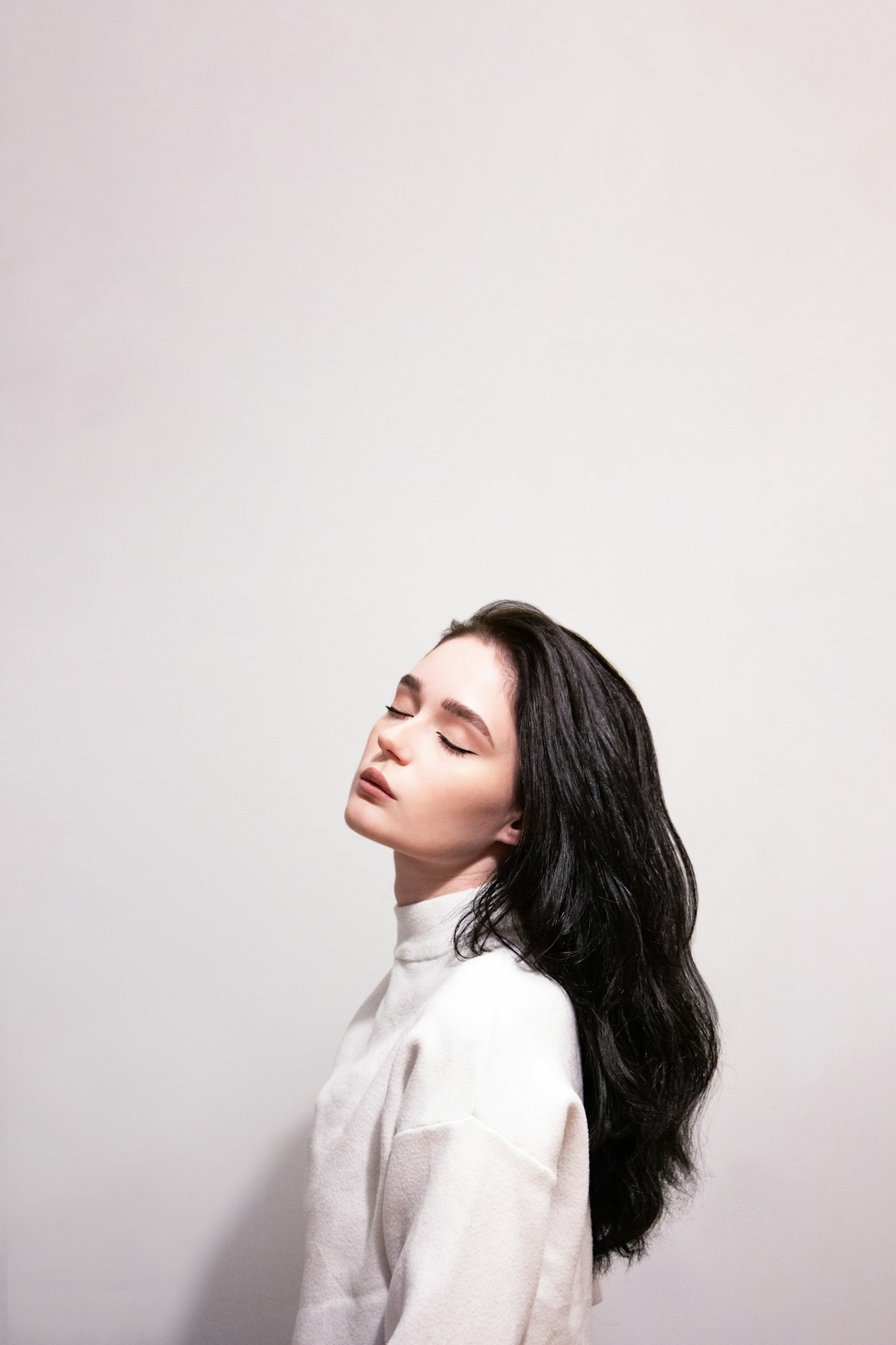Woman with long black hair standing in front of a wall