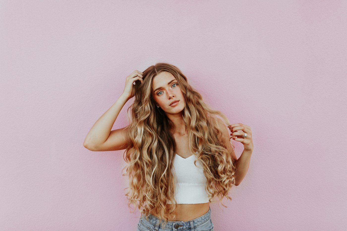 Woman with long hair standing next to a pink wall