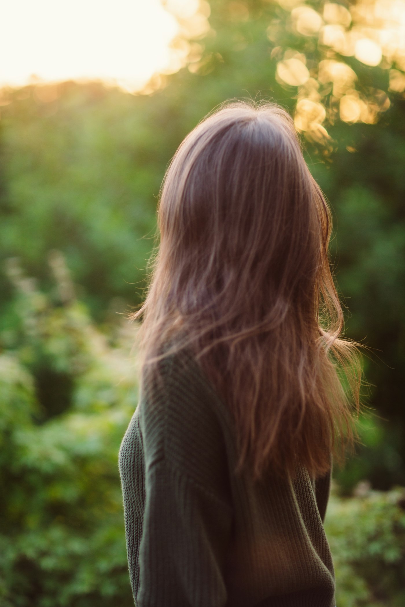 Woman with long hair standing in front of trees