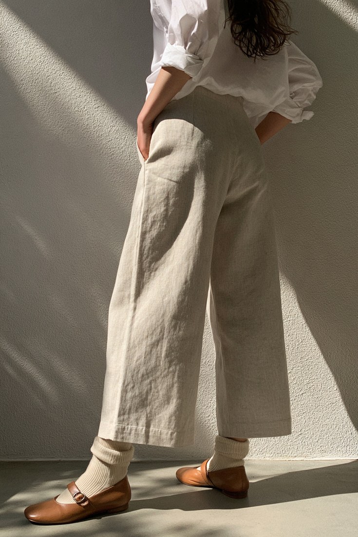 Woman in cropped stone wide-leg trousers, ivory ankle socks and tan Mary Jane flats