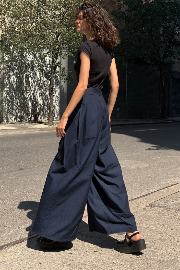 Woman in navy wide-leg trousers, fitted black top and black platform Mary Janes