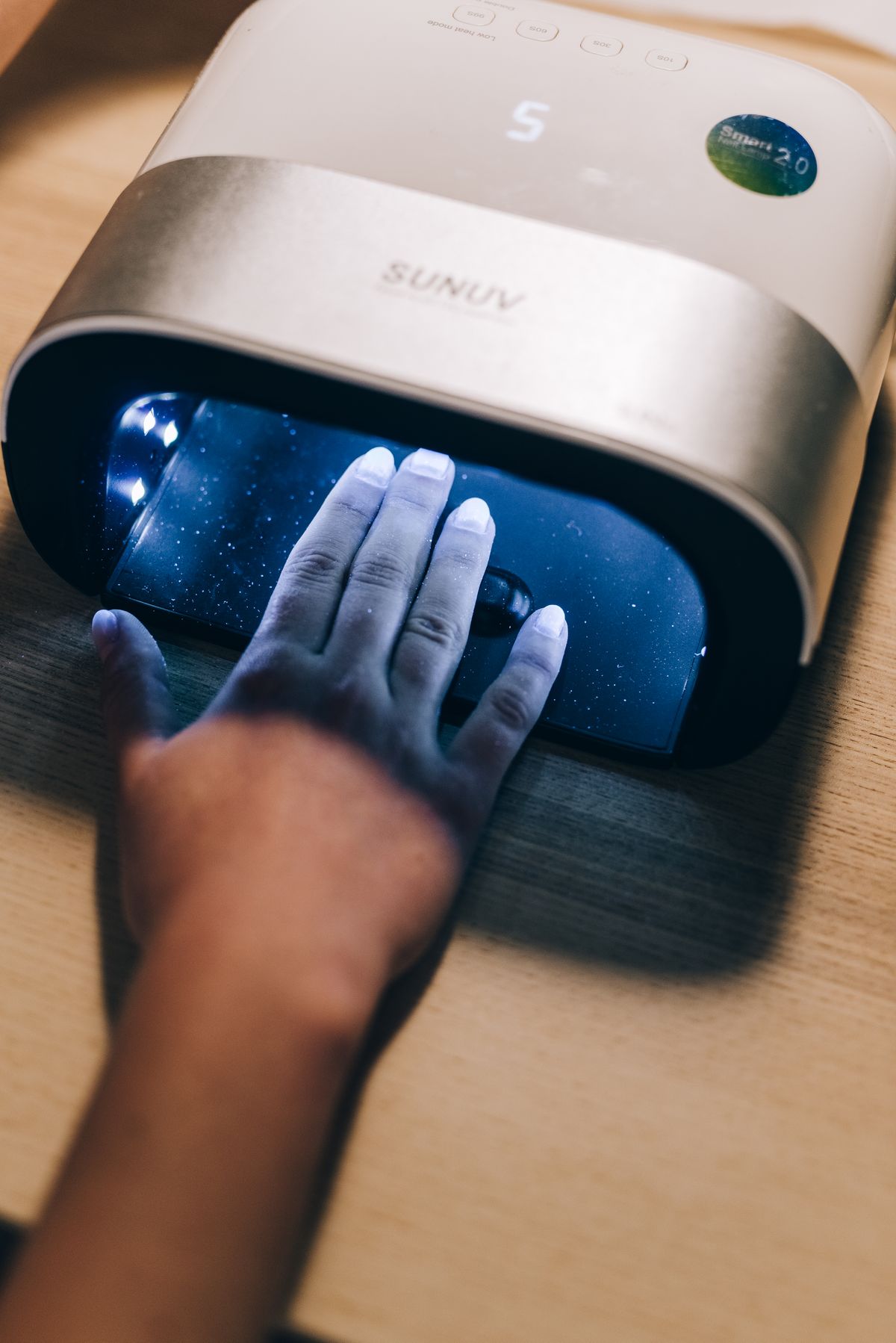 Hand placed under a glowing blue UV nail lamp