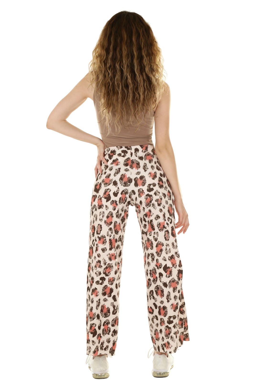 Woman with long curly hair wearing a tailored top and trousers in a neutral outfit