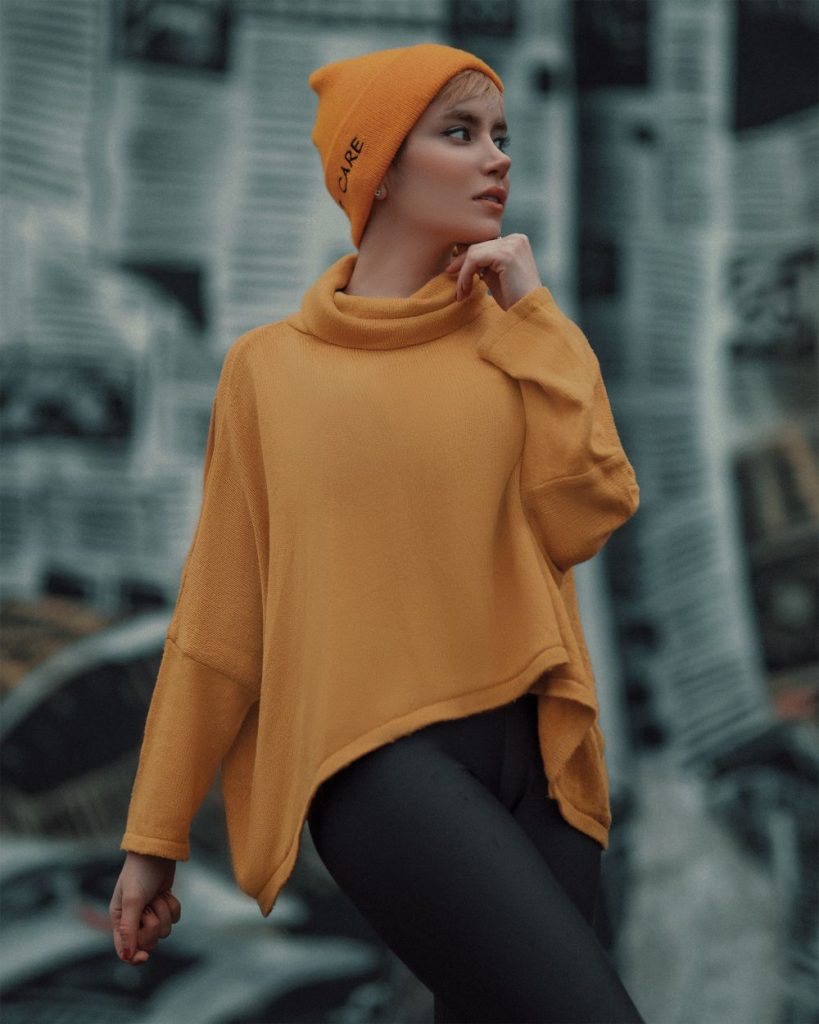 Woman in a mustard high-neck sweater and a matching mustard beanie looking to the side