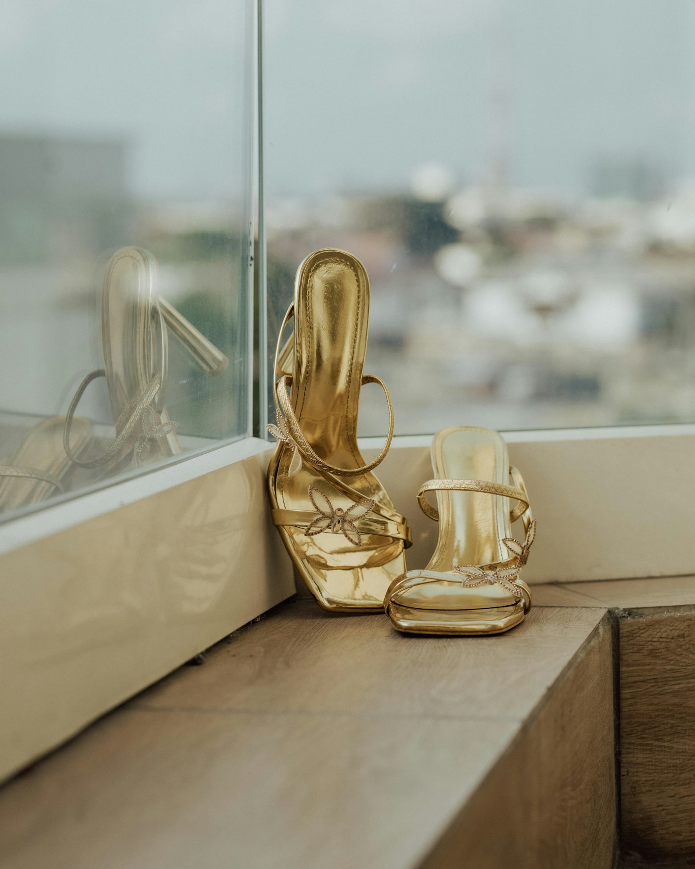 Pair of pale gold high-heeled sandals on a ledge