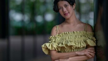 Woman in a green dress leaning against a wall