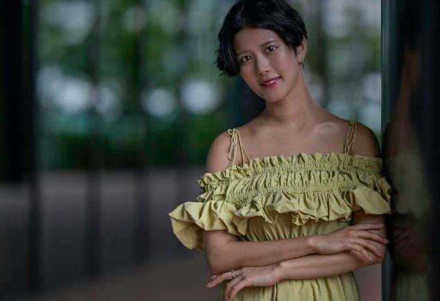 Woman in a green dress leaning against a wall