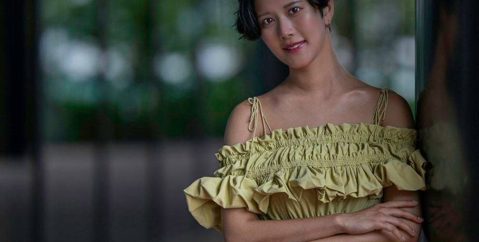 Woman in a green dress leaning against a wall