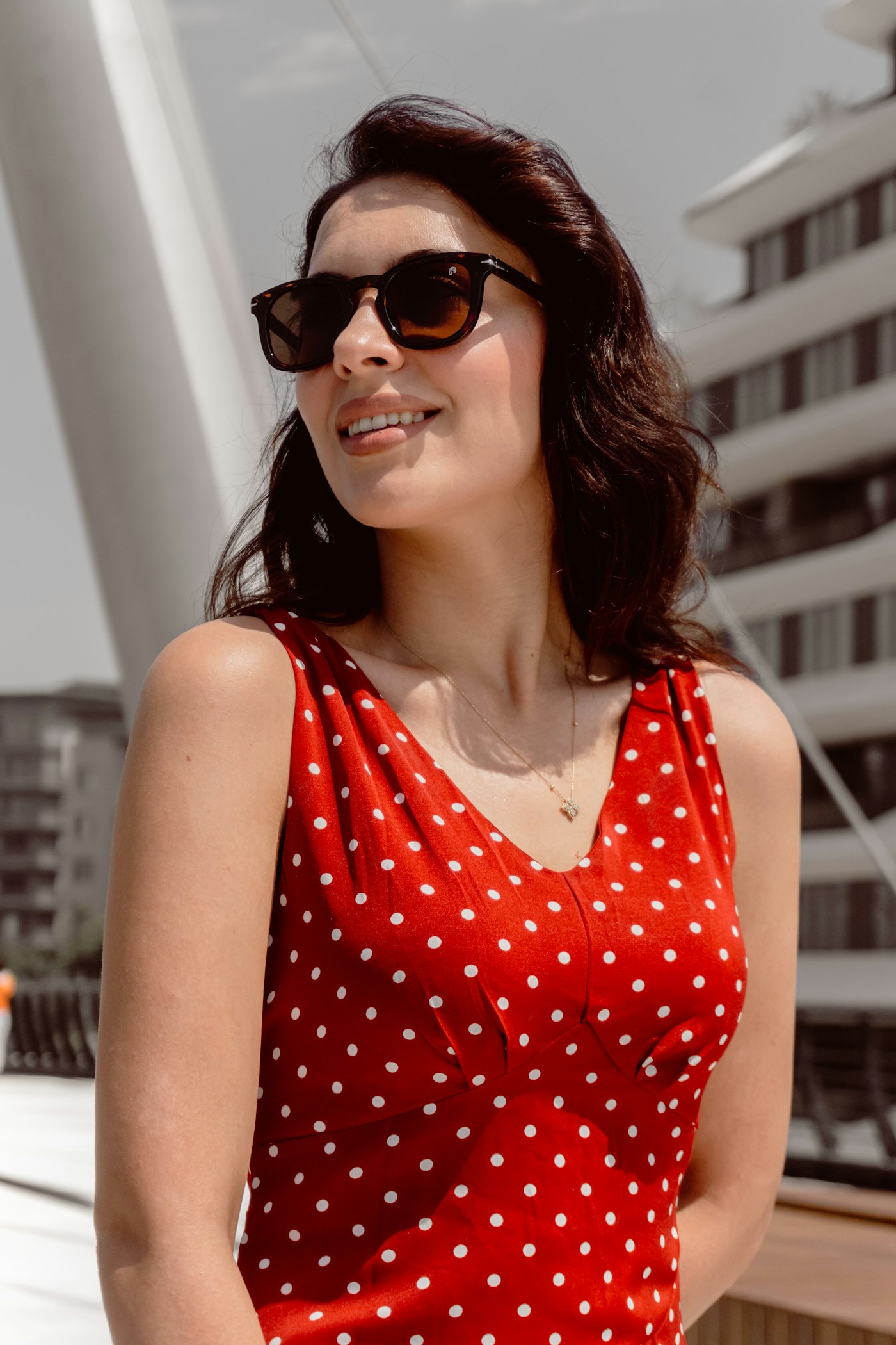 Woman in a red polka dot dress and sunglasses outdoors