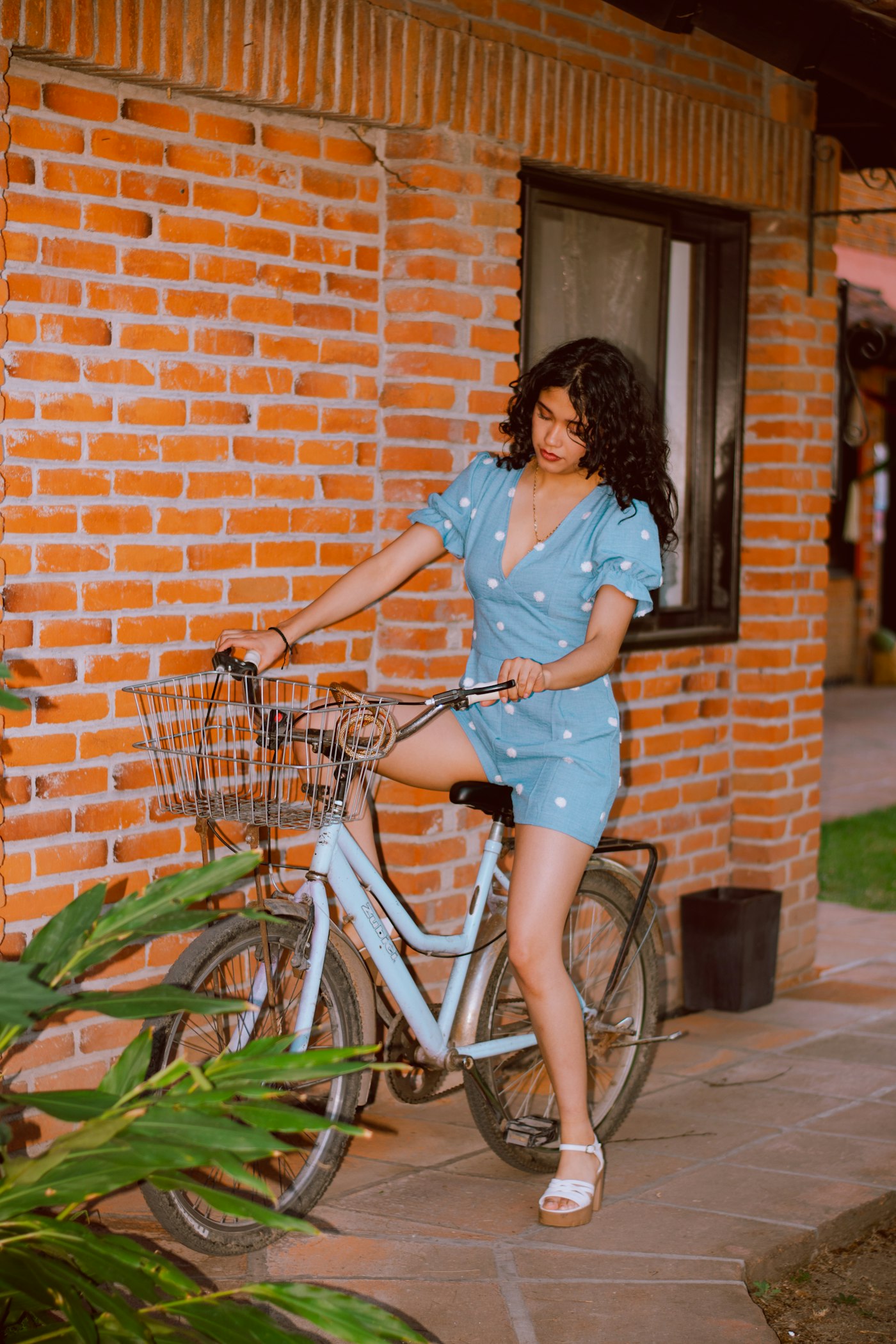 Young woman in a blue polka dot romper with a bicycle