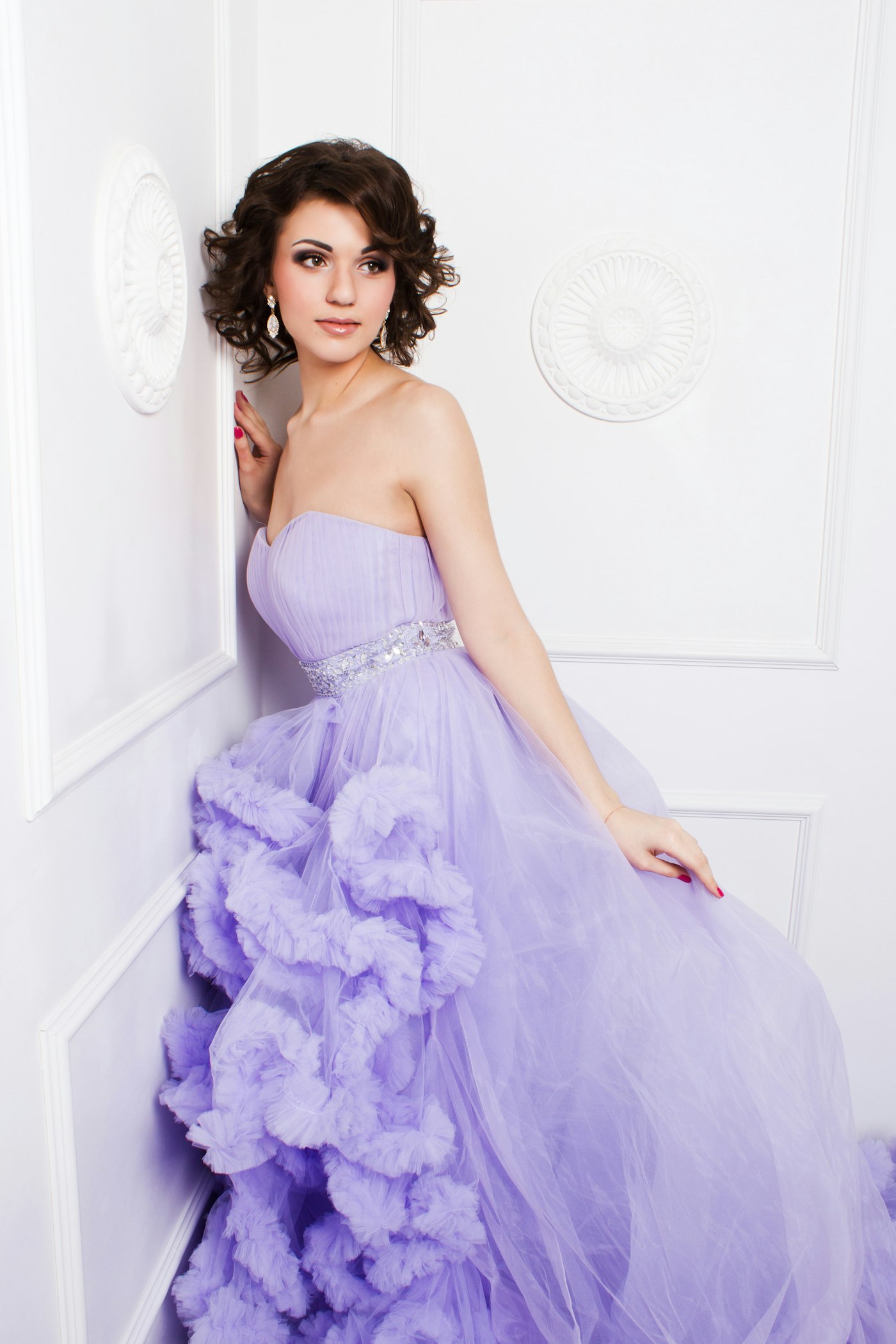 Woman in a purple strapless dress leaning on a wall