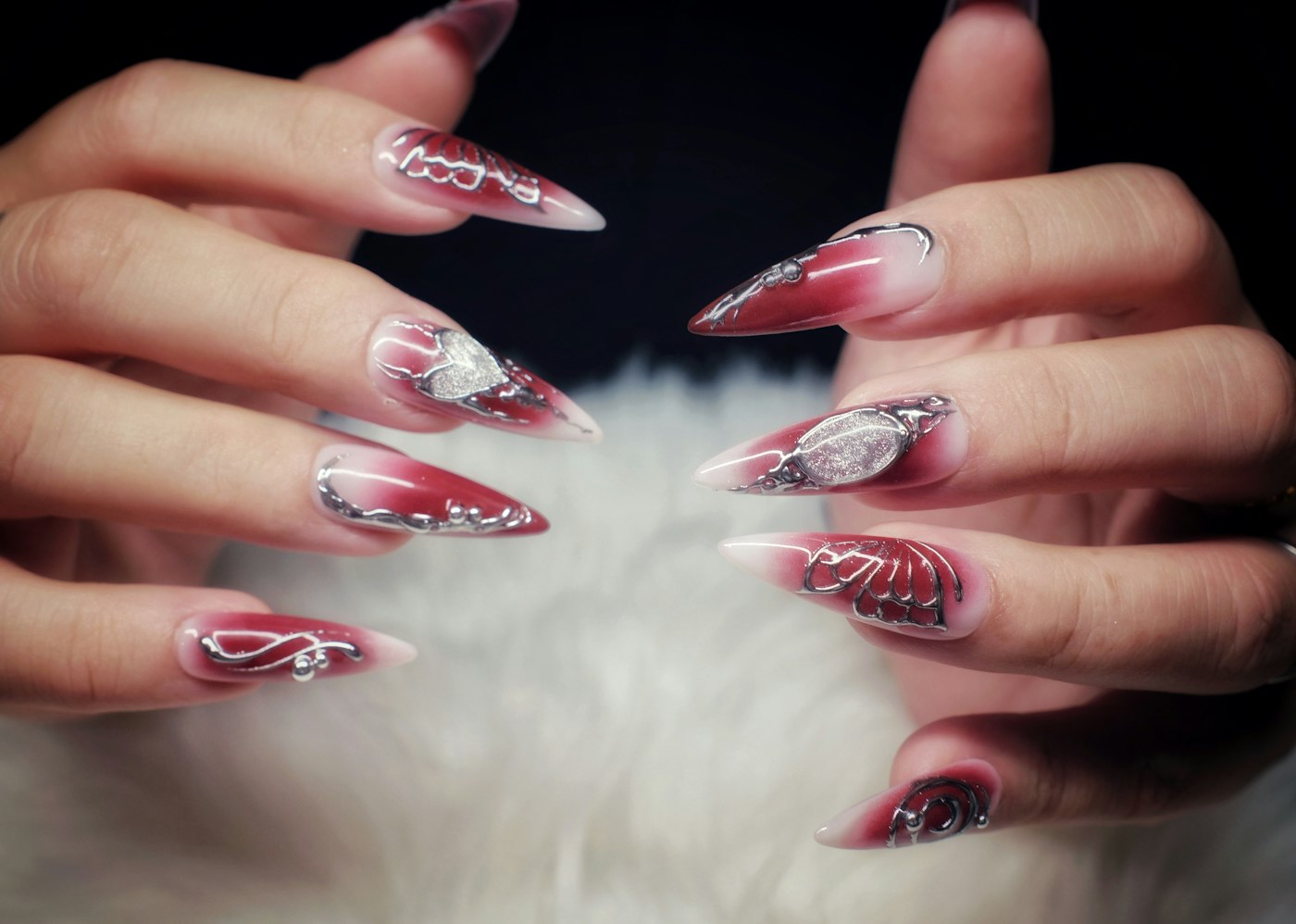 Hands with long red and white stiletto nails, a bold candy cane style idea