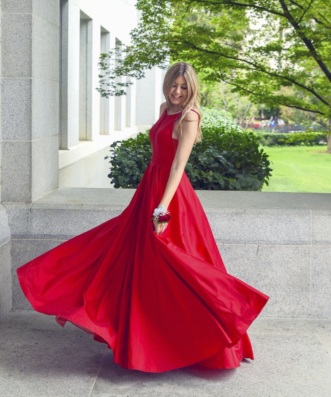 Woman in a red sleeveless dress standing against a plain background