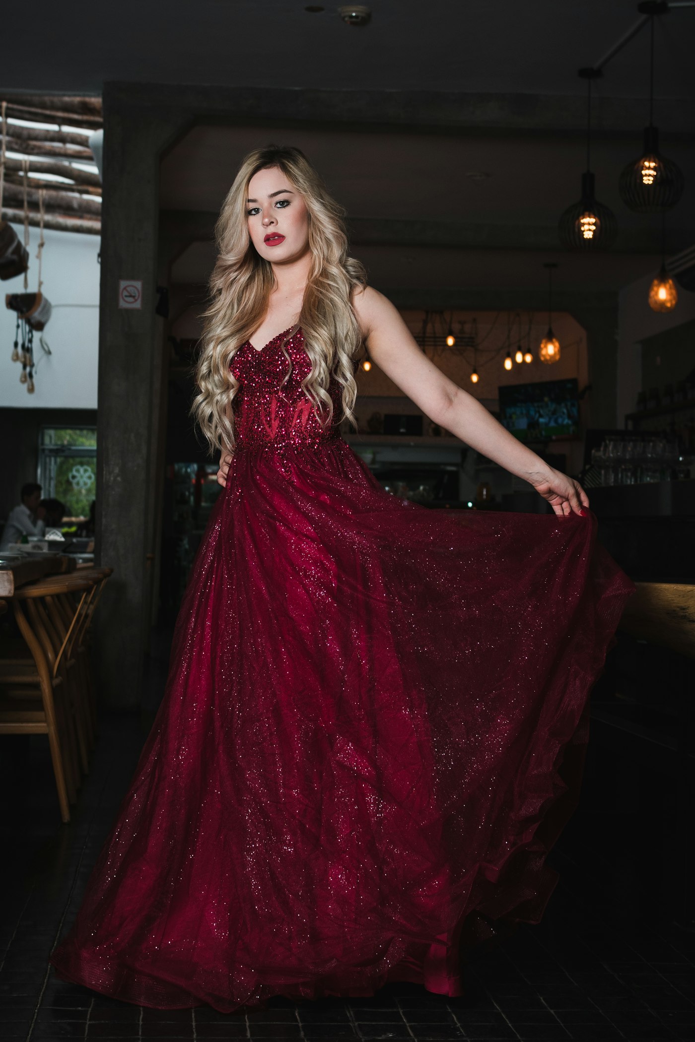 Woman in a sparkling red gown posing indoors