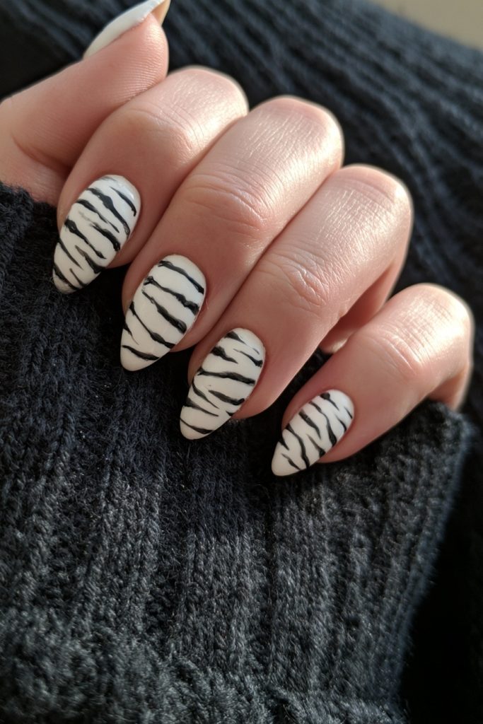 Hand with almond white nails and black skeleton rib lines resting on a dark knit sweater
