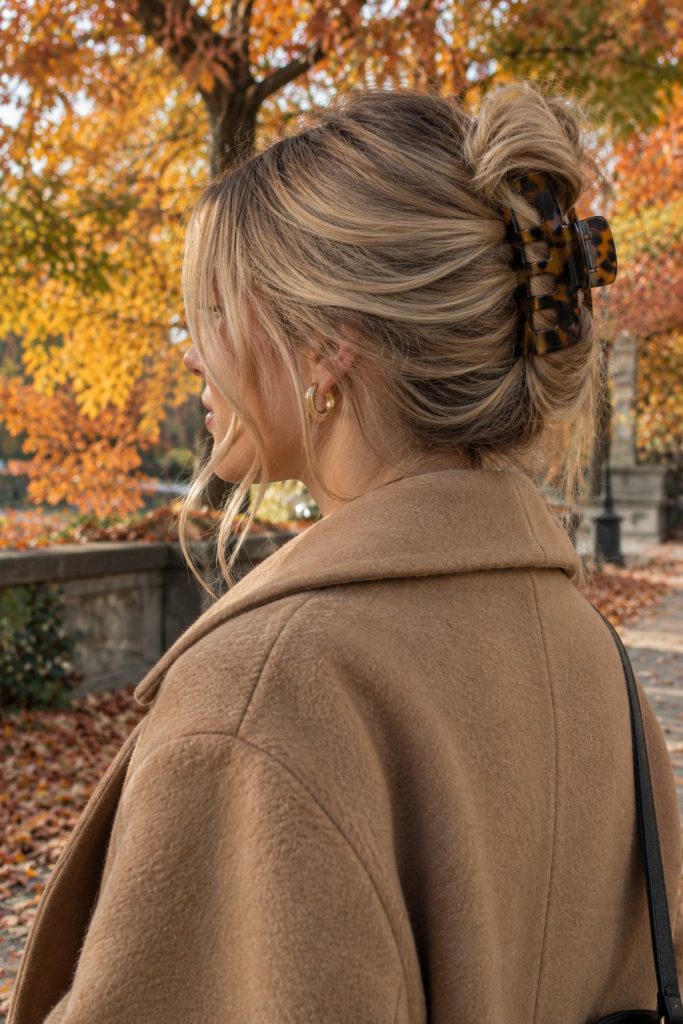 Blonde hair twisted up with a tortoiseshell claw clip and a camel wool coat