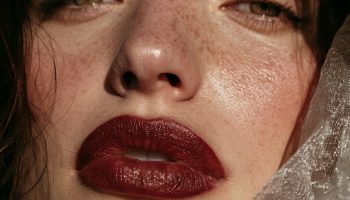 Close up of a woman with a deep wine lip and warm bronze tones in soft autumn light