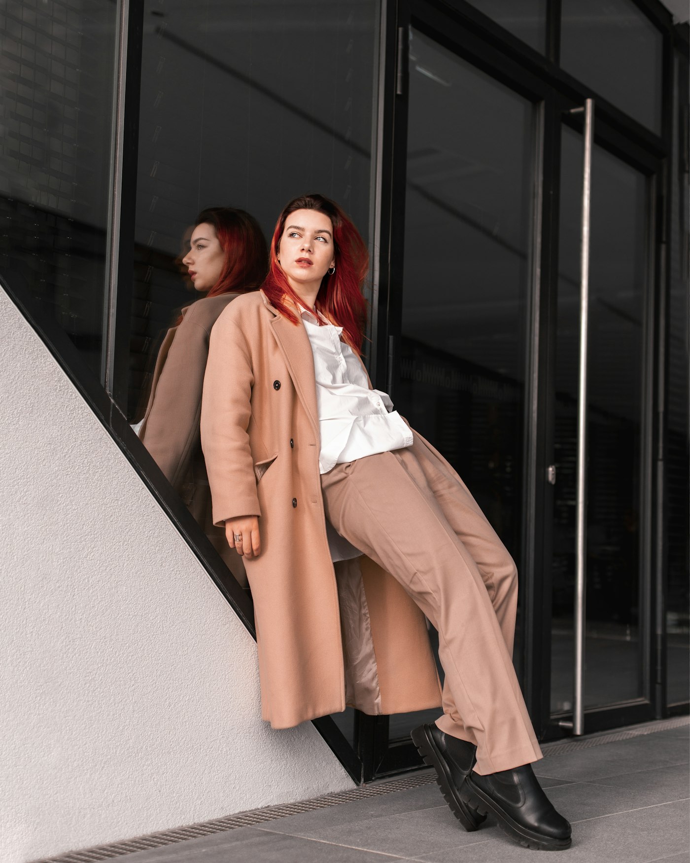Woman in a trench coat leaning against a wall