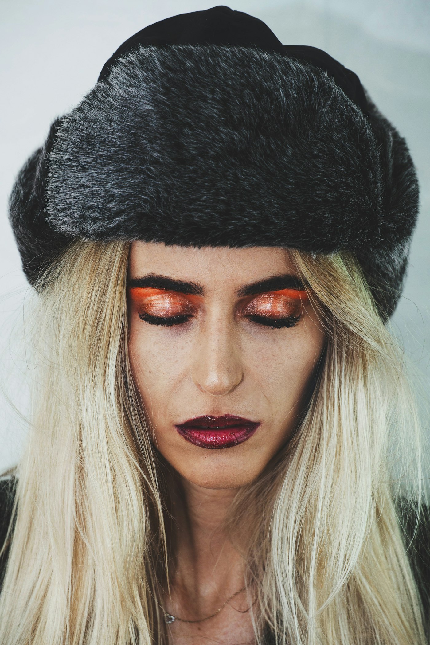 Woman with vibrant burnt orange eyeshadow in a furry hat