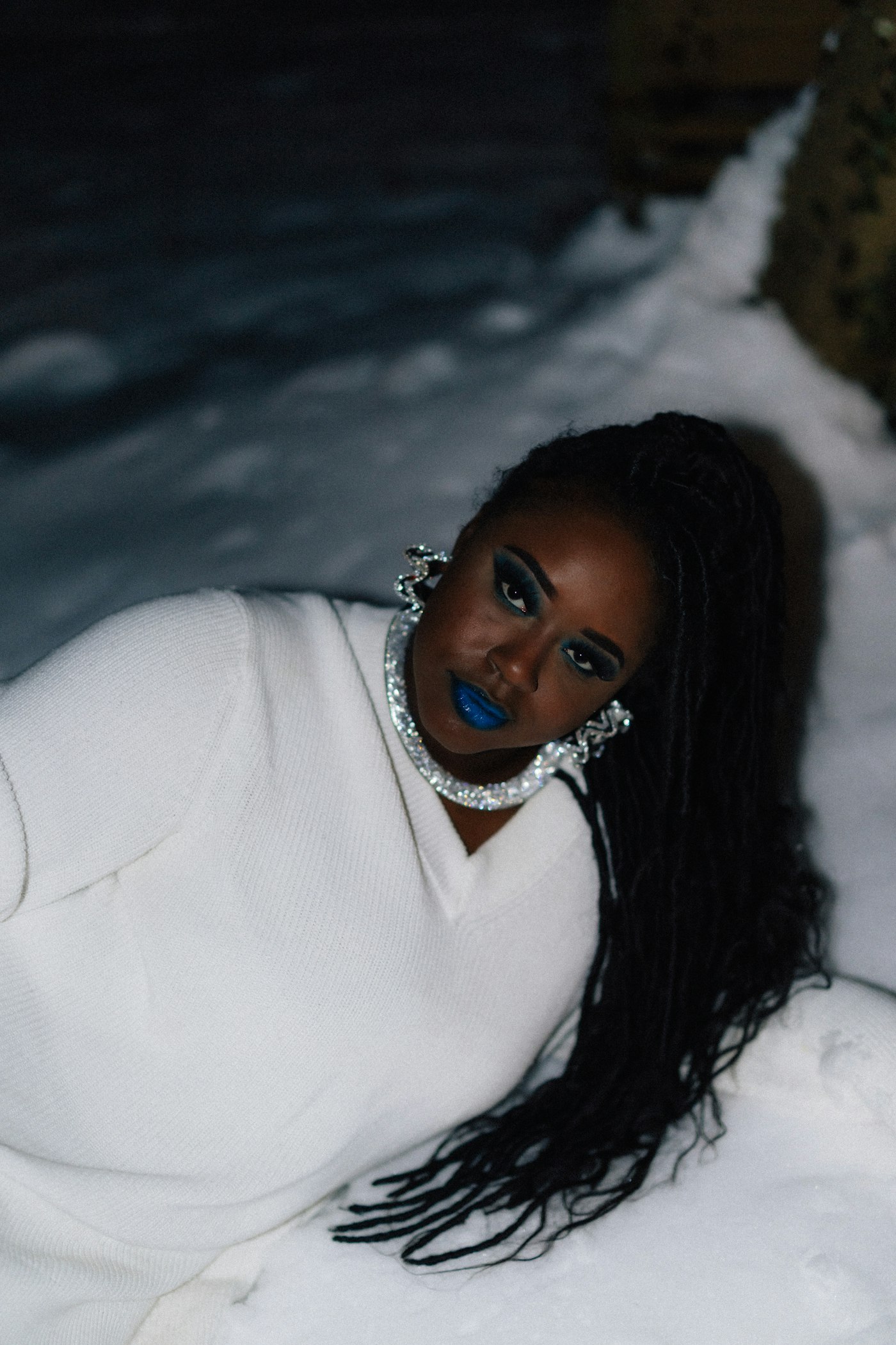 Woman with bold blue lipstick and large earrings in snow