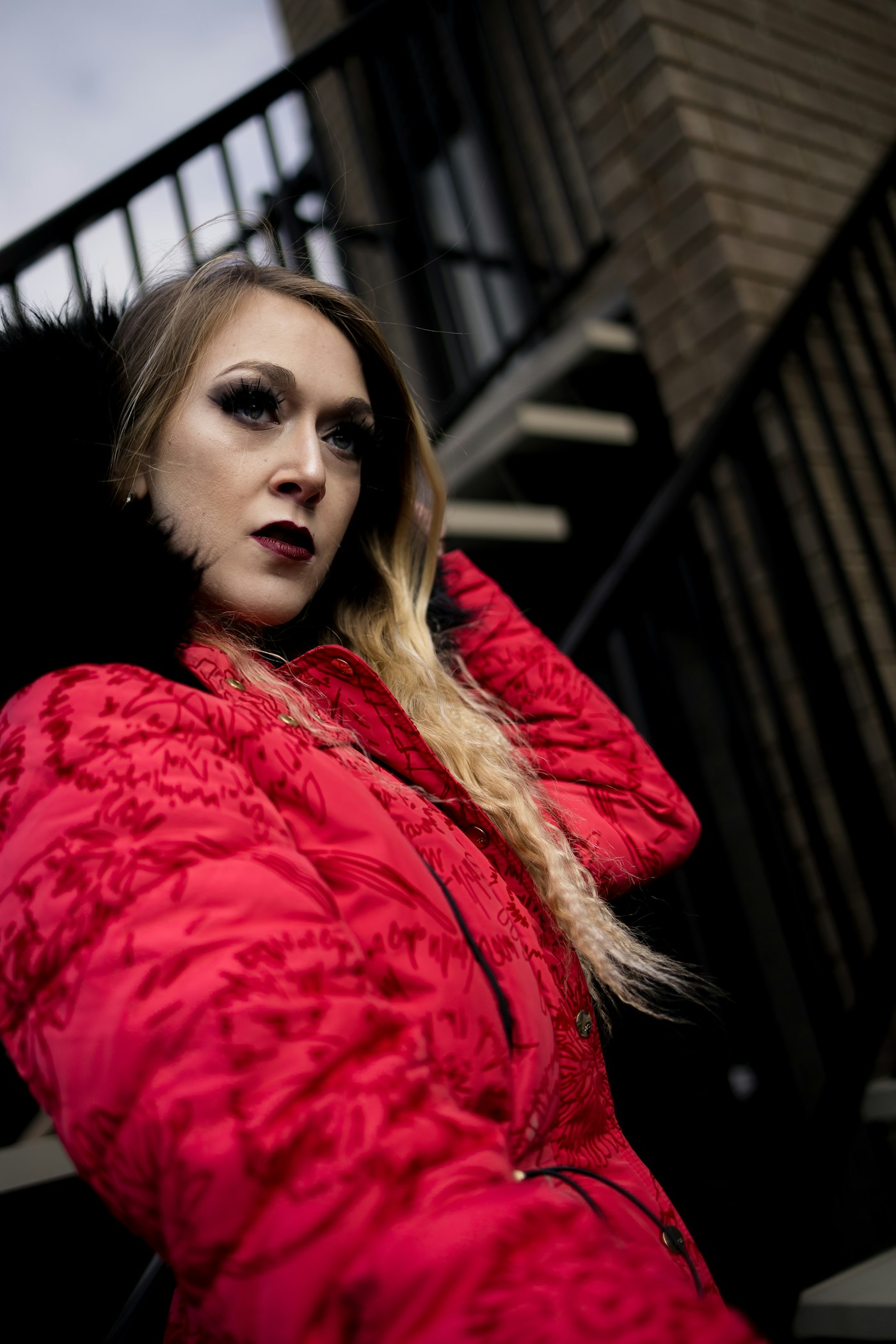 Stylish woman in a red coat with dark smoky makeup outdoors
