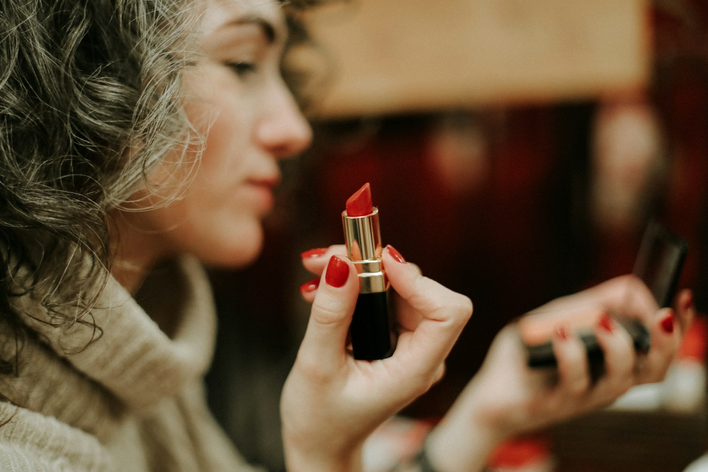 Woman in a grey sweater holding a lipstick