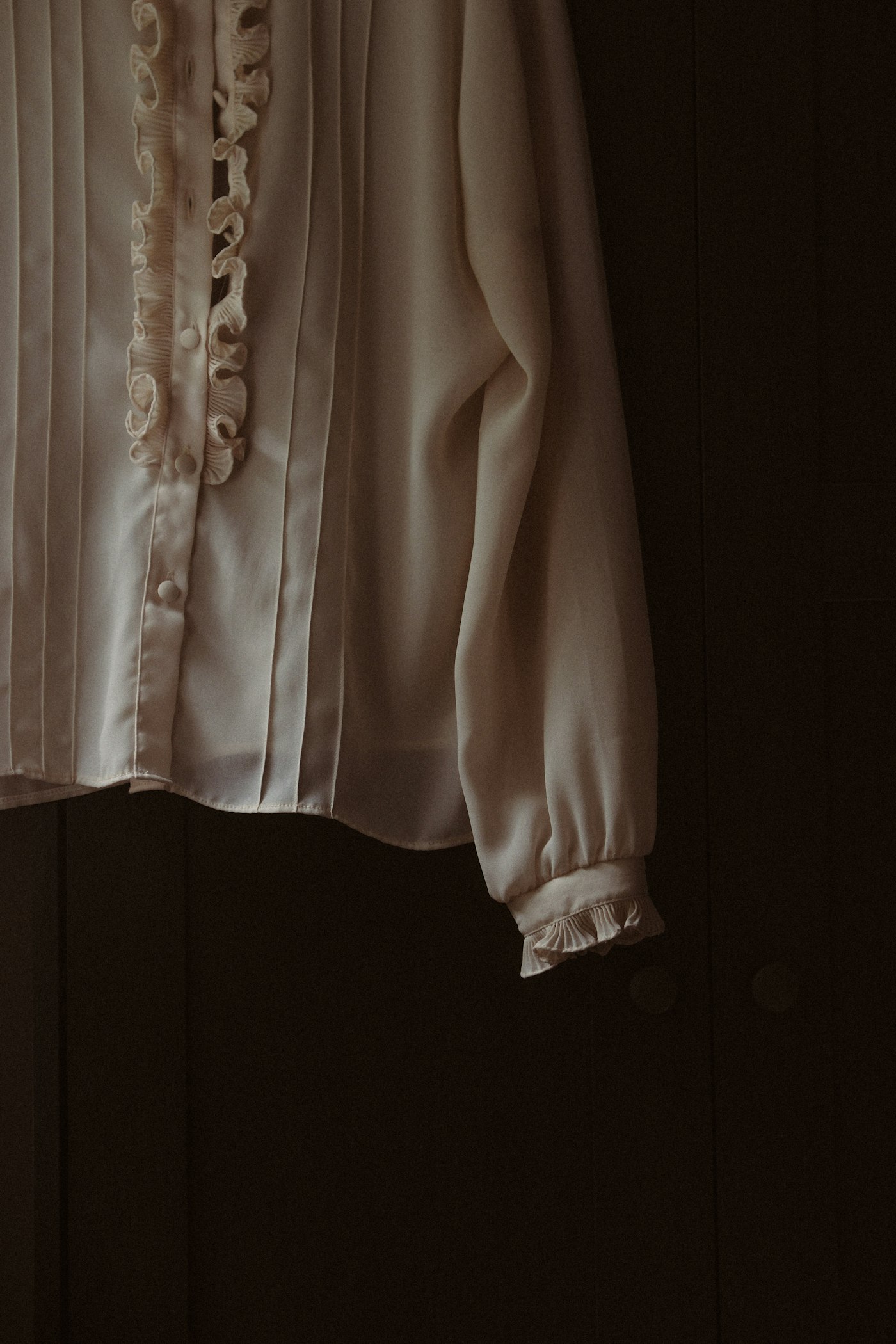 White blouse with ruffles hanging from a hook, an example of the romantic detail to look for