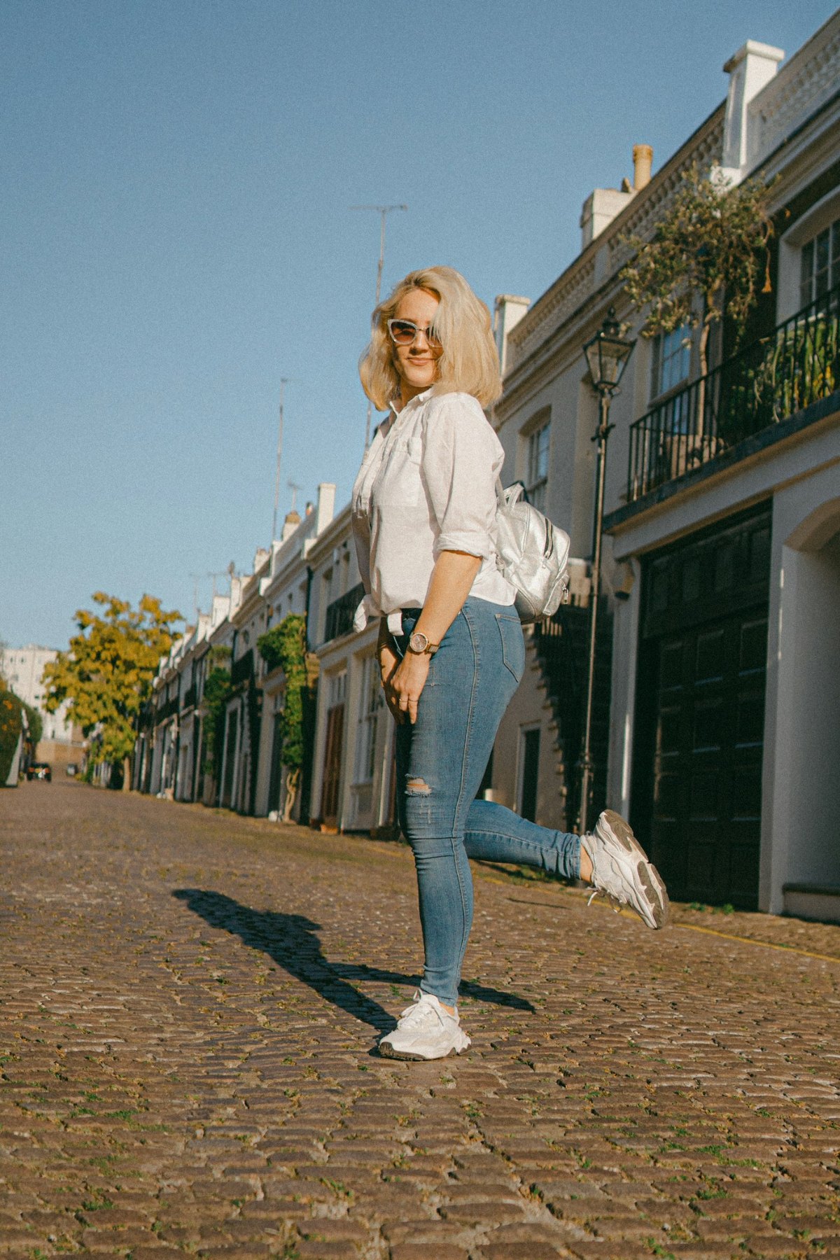 Woman in a white shirt and blue jeans on a concrete floor
