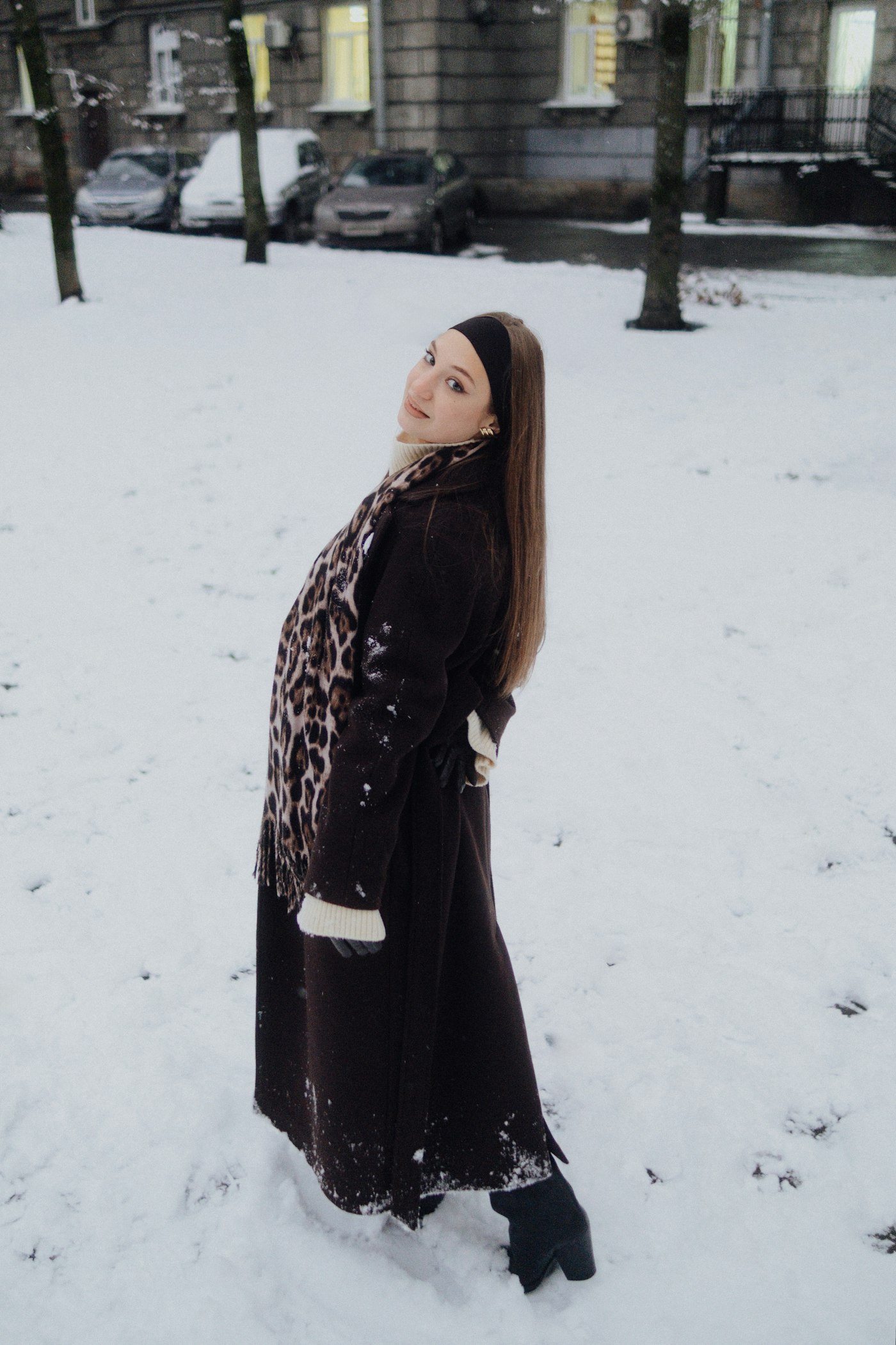 Young woman in a winter coat standing in the snow