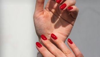 Close up of a hand with a rich dark red manicure, winter nail colors