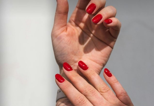 Close up of a hand with a rich dark red manicure, winter nail colors