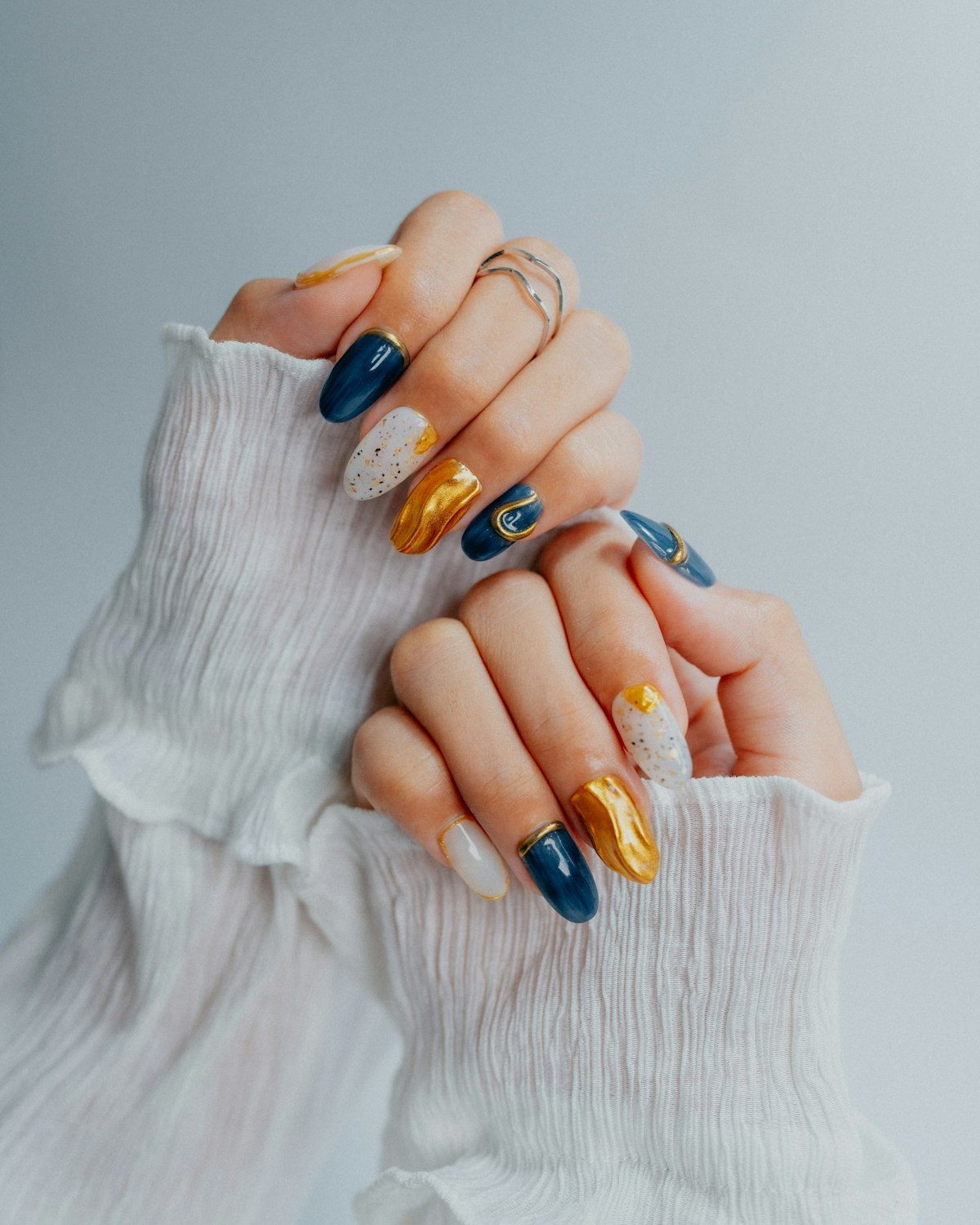 Hands with ornate navy and gold nail art