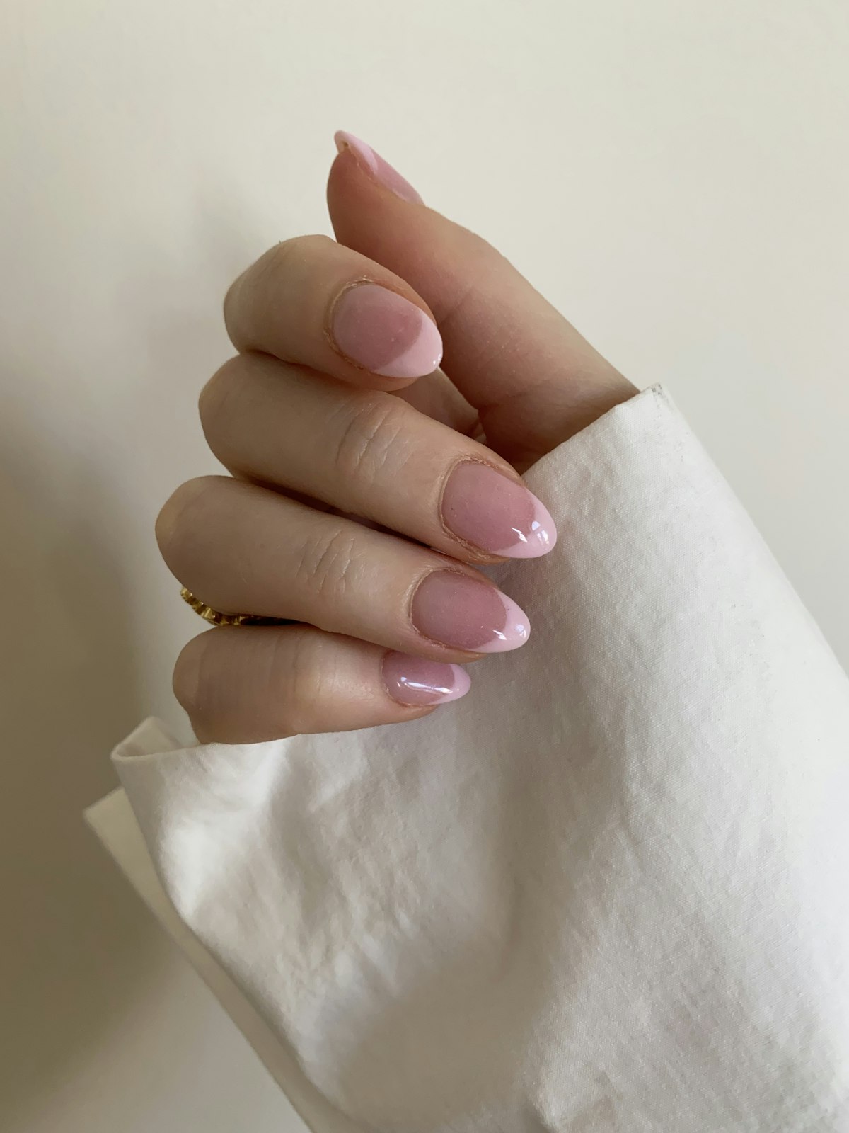 Hand with a pink manicure on a white surface