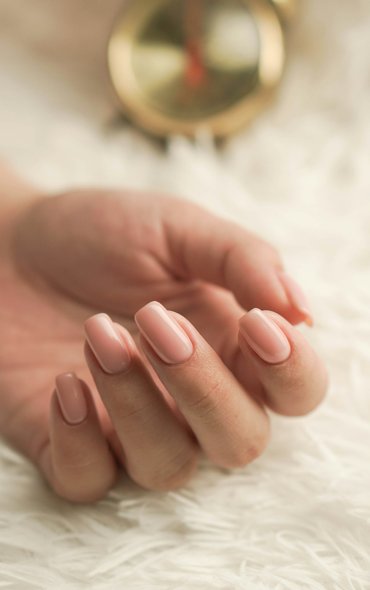 Hand with light pink glossy manicured nails