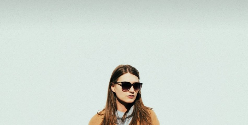 Woman in a tan wool coat and sunglasses on a winter day