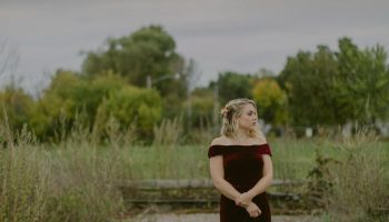 Woman in a deep maroon dress standing outdoors, a winter wedding guest color idea