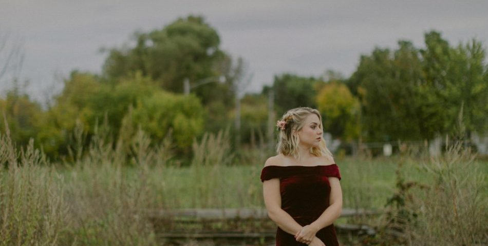 Woman in a deep maroon dress standing outdoors, a winter wedding guest color idea