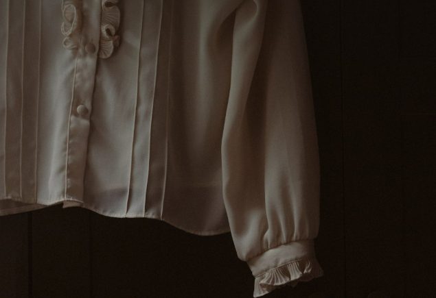 Ruffled white blouse hanging on a hook, a styling cue for the ruffled jacket and jeans look