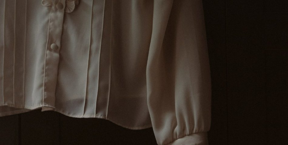 Ruffled white blouse hanging on a hook, a styling cue for the ruffled jacket and jeans look